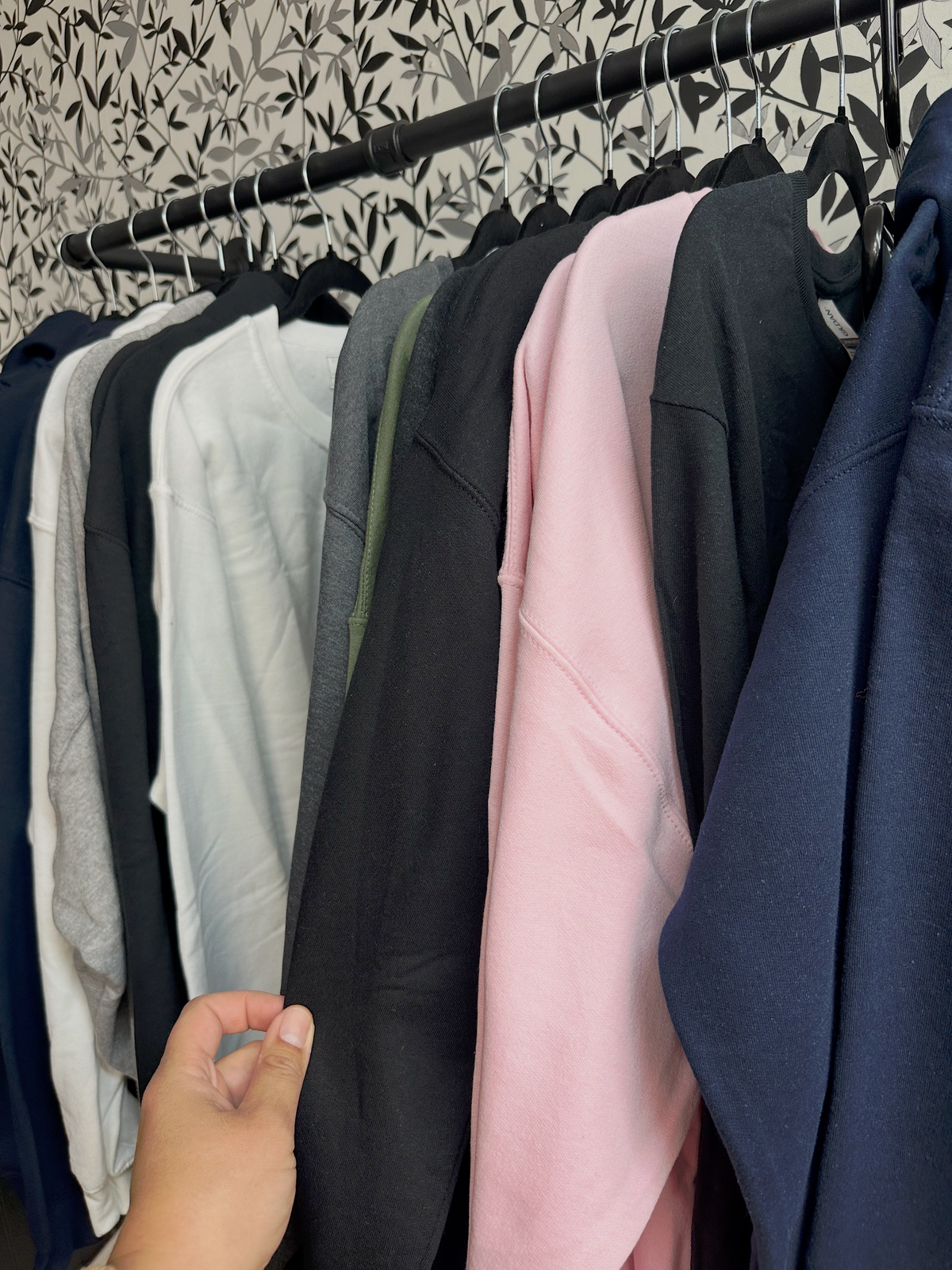 Custom hoodies and t-shirts on a rack at Powerful.Creative in Sydney, Nova Scotia