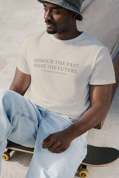Model wearing a light-colored t-shirt with the text “Honour the Past. Shape the Future. Celebrating African Heritage", seated casually on a skateboard.